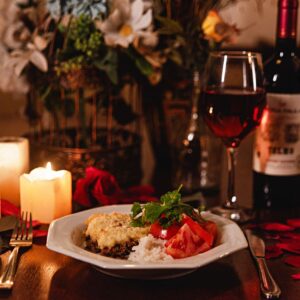 Cozy candlelit dinner featuring wine, a gourmet meal, and romantic decor with rose petals.