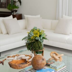 Cozy living room with a white sofa and nature-inspired decor on a glass coffee table.