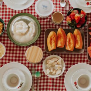 Vibrant breakfast spread featuring fresh fruits, pastries, and dairy on a checkered tablecloth.