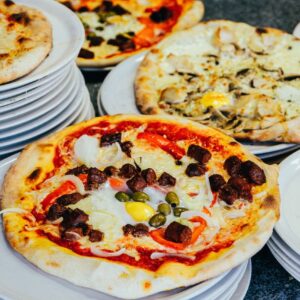 Delicious variety of gourmet pizzas elegantly presented on stacked plates, perfect for food lovers.